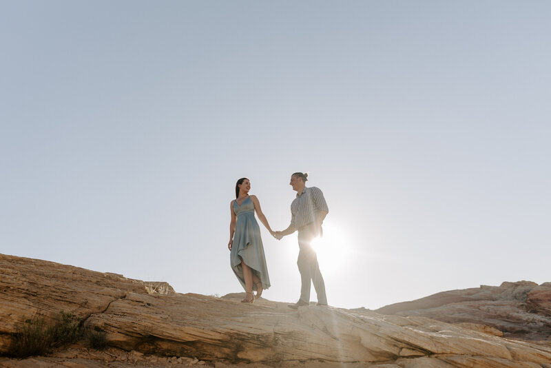 A couple holds hands on rocks at The Valley of Fire state park.
