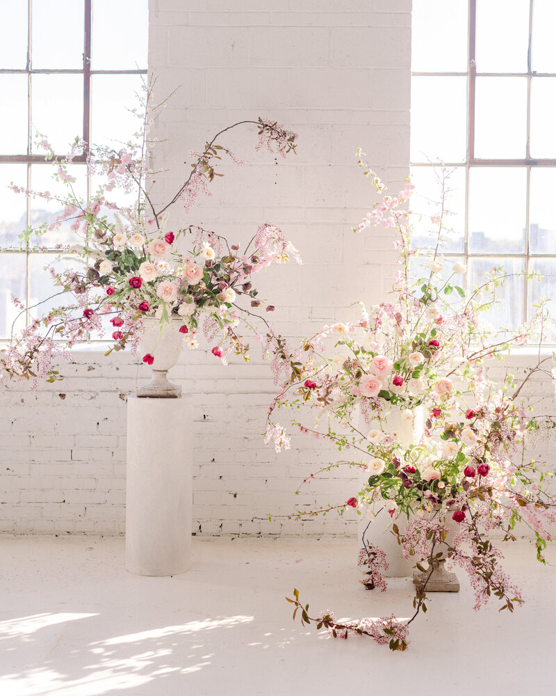 Staggered arrangements of airy, organic pink flowers for a wedding ceremony at L'Eloi. 