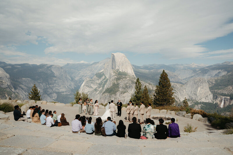 Glacier Point Amphitheater Wedding  with guests seated in the amphitheater and Half Dome in the background