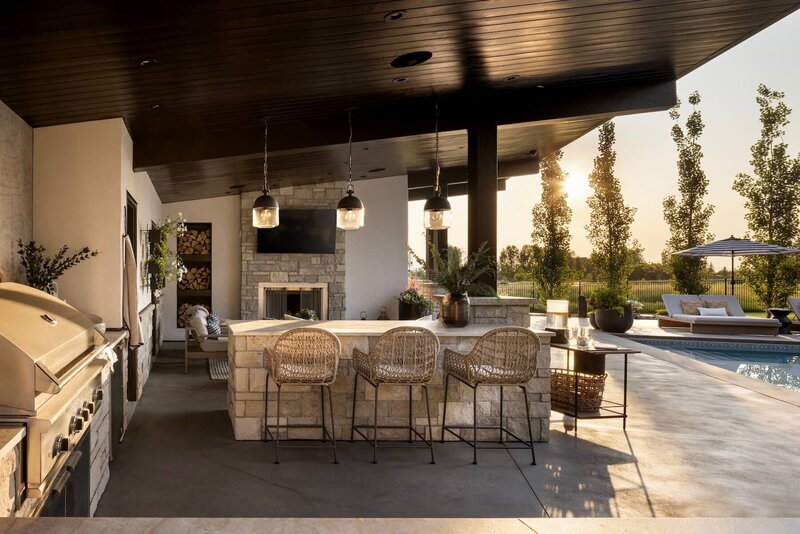 An outdoor kitchen with stone features, accent lighting and outdoor fireplace. 