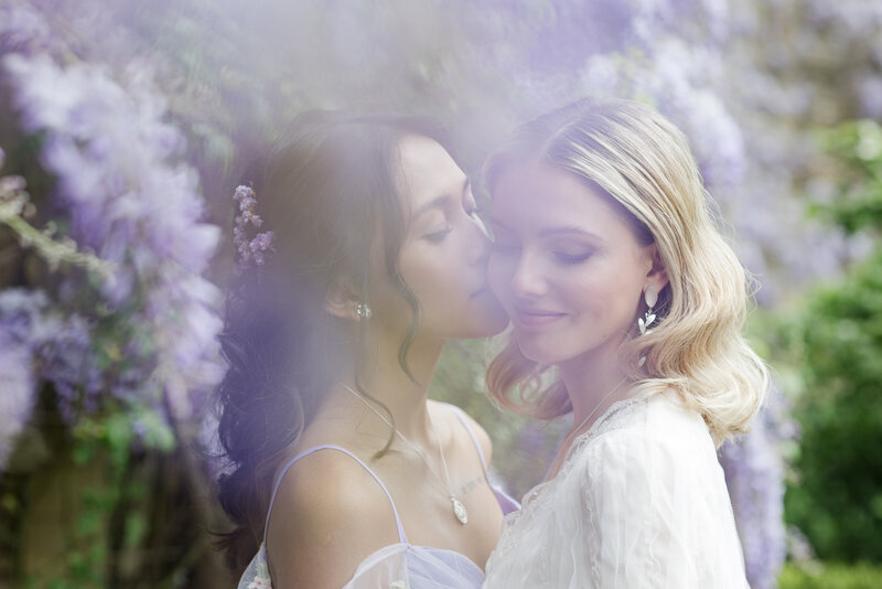 two beautiful brides in love kissing by wisteria at Euridge Manor wedding venue in the cotswolds