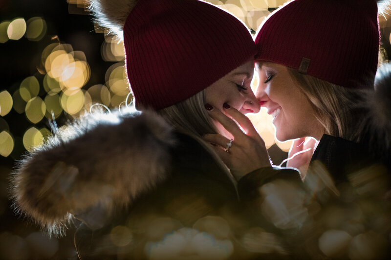 Two women in red beanies about to kiss.