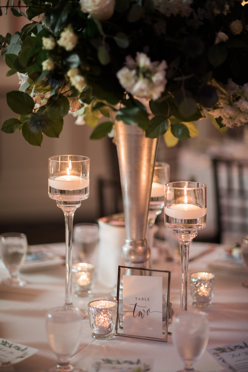 Place setting with long stemmed tea light holders and table number and flowers