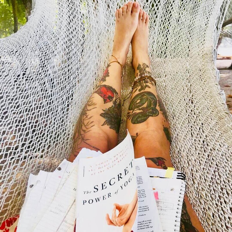 Student reading yoga philosophy in a peaceful hammock setting.