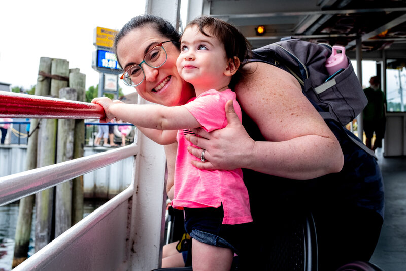 A woman holding a child on a ferry.