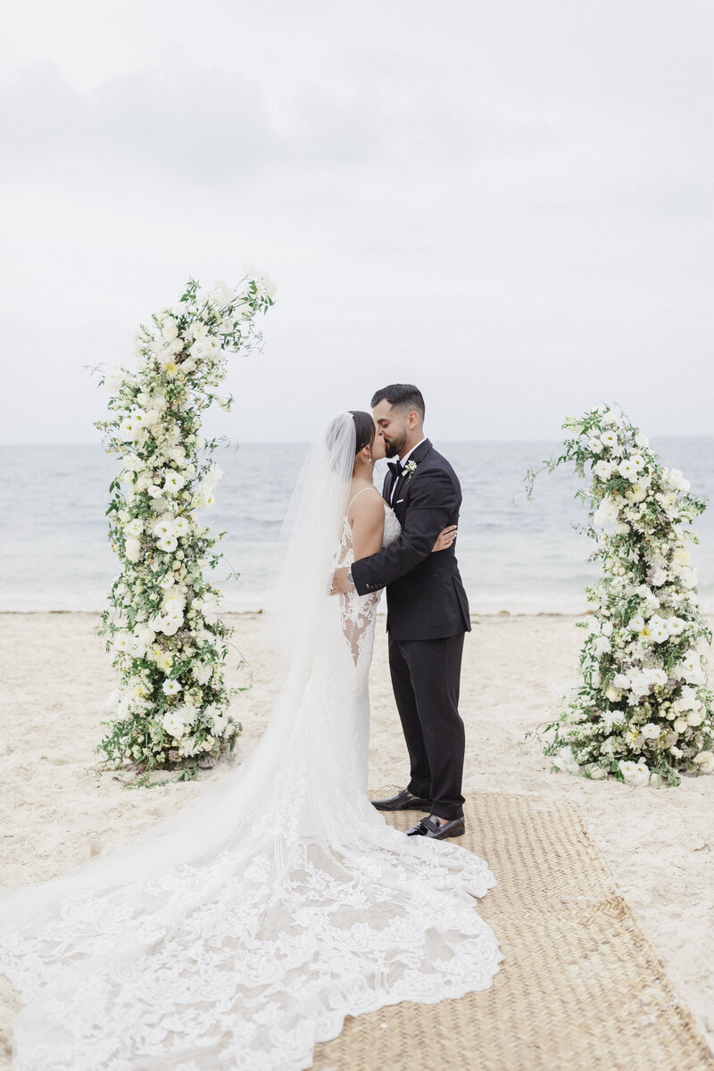 bride and groom kiss at beach wedding