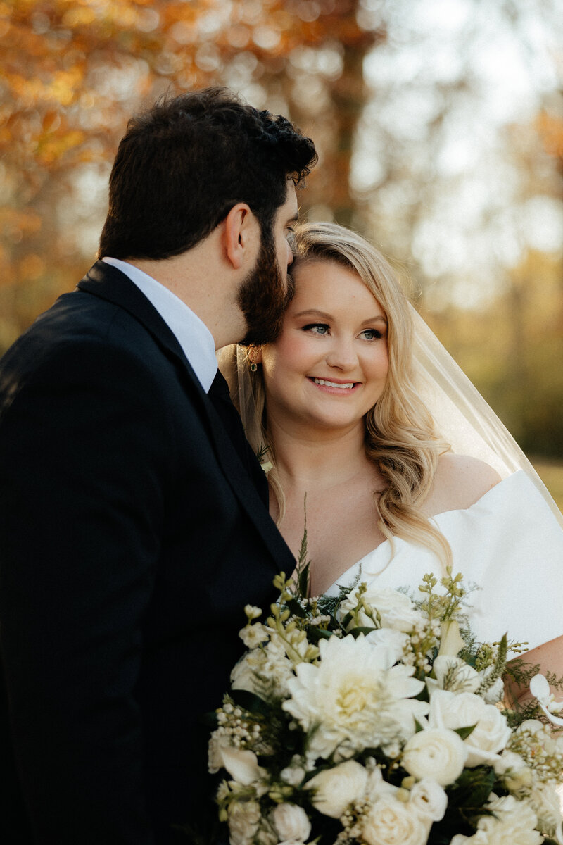 A groom kissing his bride's temple.