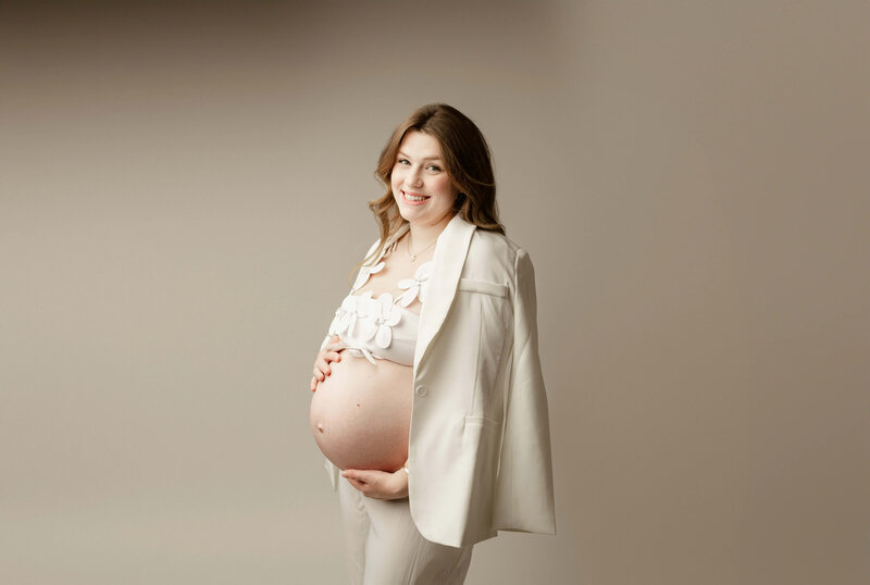 Standing maternity portrait with cream  blazer and floral bra in Maple Grove 