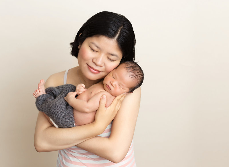 mom holding baby boy grey pants