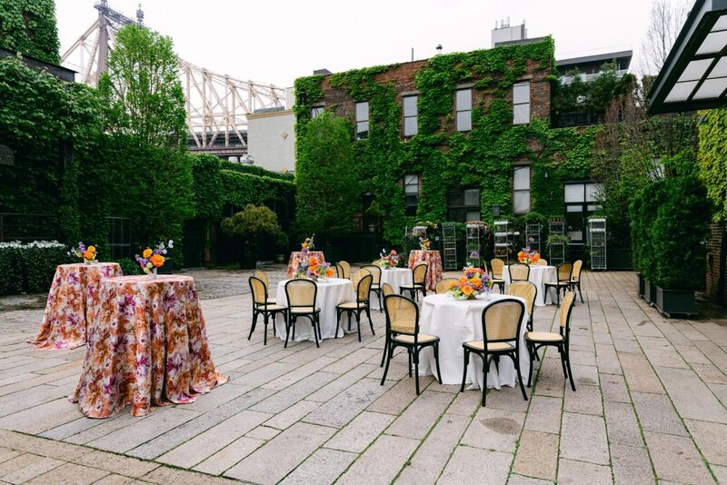 Sophisticated outdoor tented wedding reception with long tables, white floral centerpieces, and wooden chairs in a natural setting