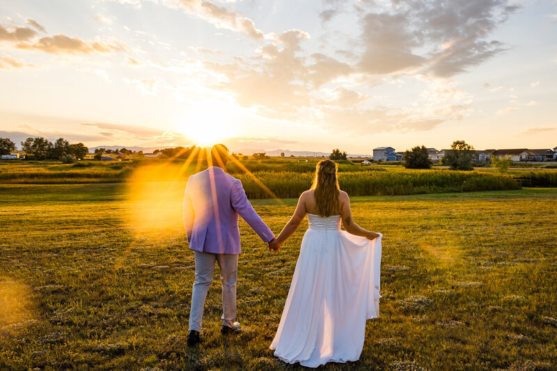 Bride and groom standing on a hill at sunset with golden light behind them at Still Waters Ranch in Colorado.