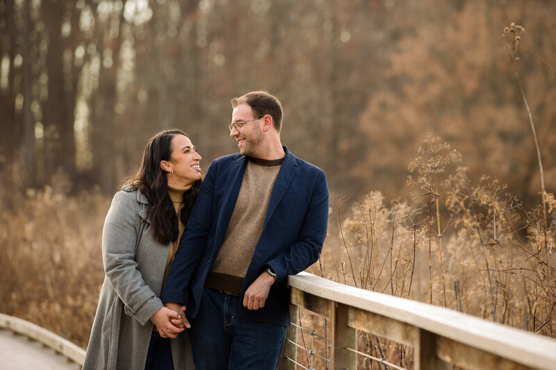 Couple standing on a scenic walkway overlooking a lush field during their engagement session at Longwood Gardens, capturing timeless romance.