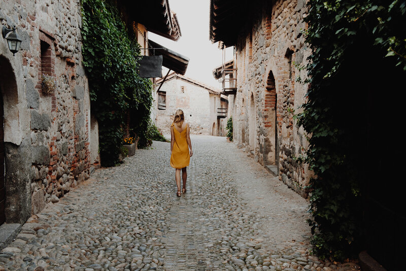 Woman walking on a cobblestone street in a yellow dress, symbolizing clarity and balance on a stress-free journey.