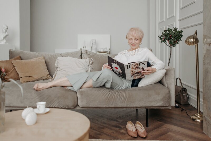 a woman reads and relaxes while a nanny watches her kids