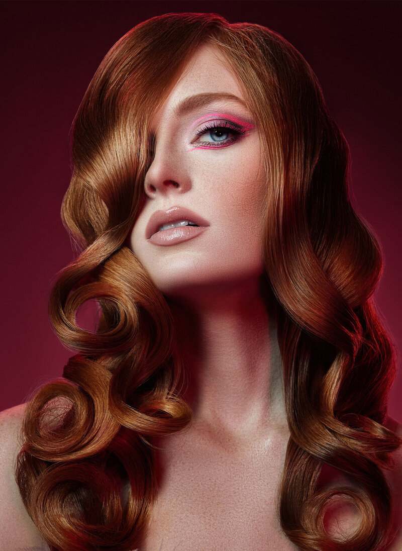 Striking portrait of Denya with voluminous curly hair and vibrant makeup, captured by Ylva Erevall.
