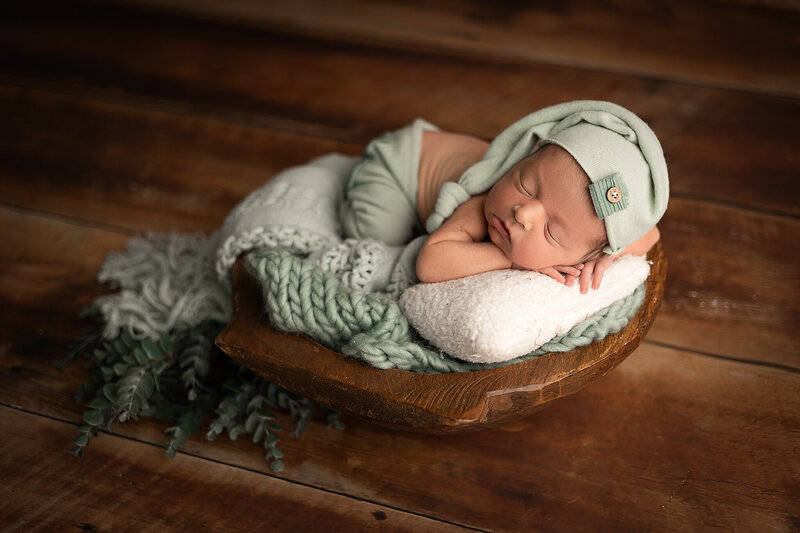sleeping newborn baby posed on hands on sage green  blanket