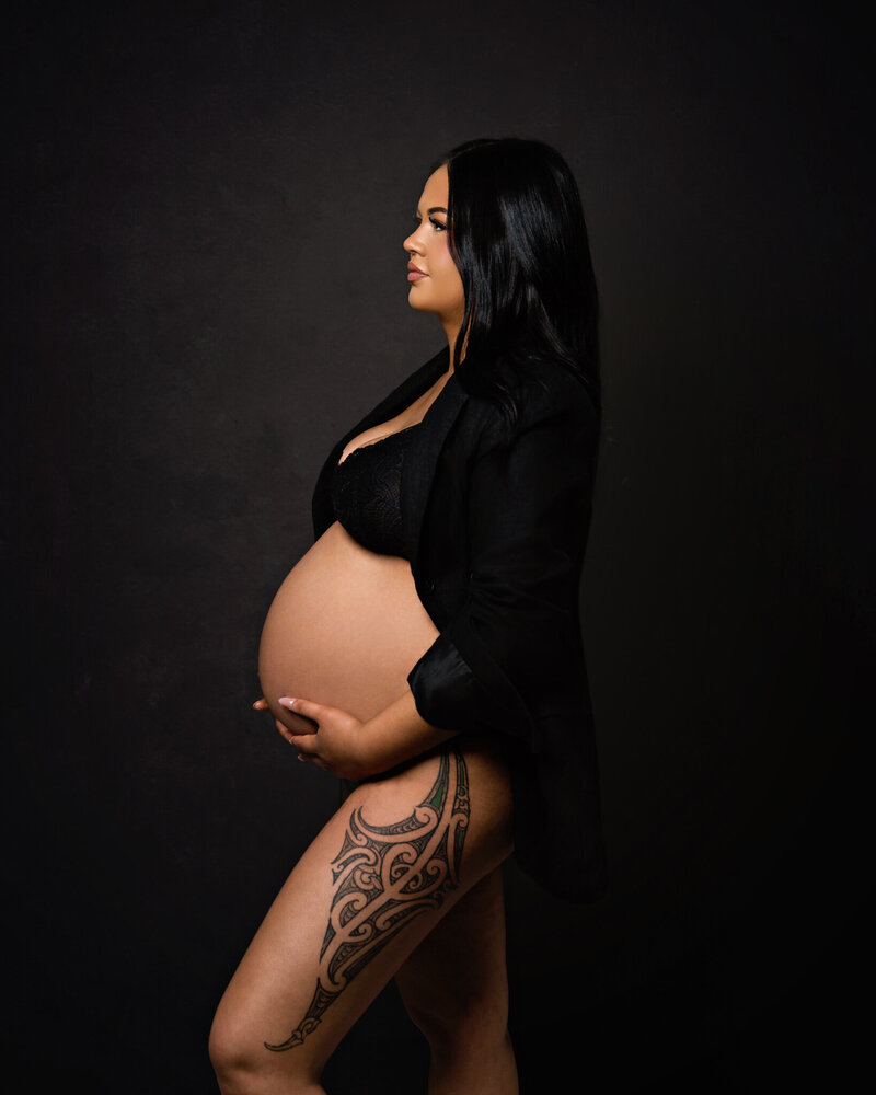 expecting mother in studio shoot, maori tatoo on leg in black bra and jacket