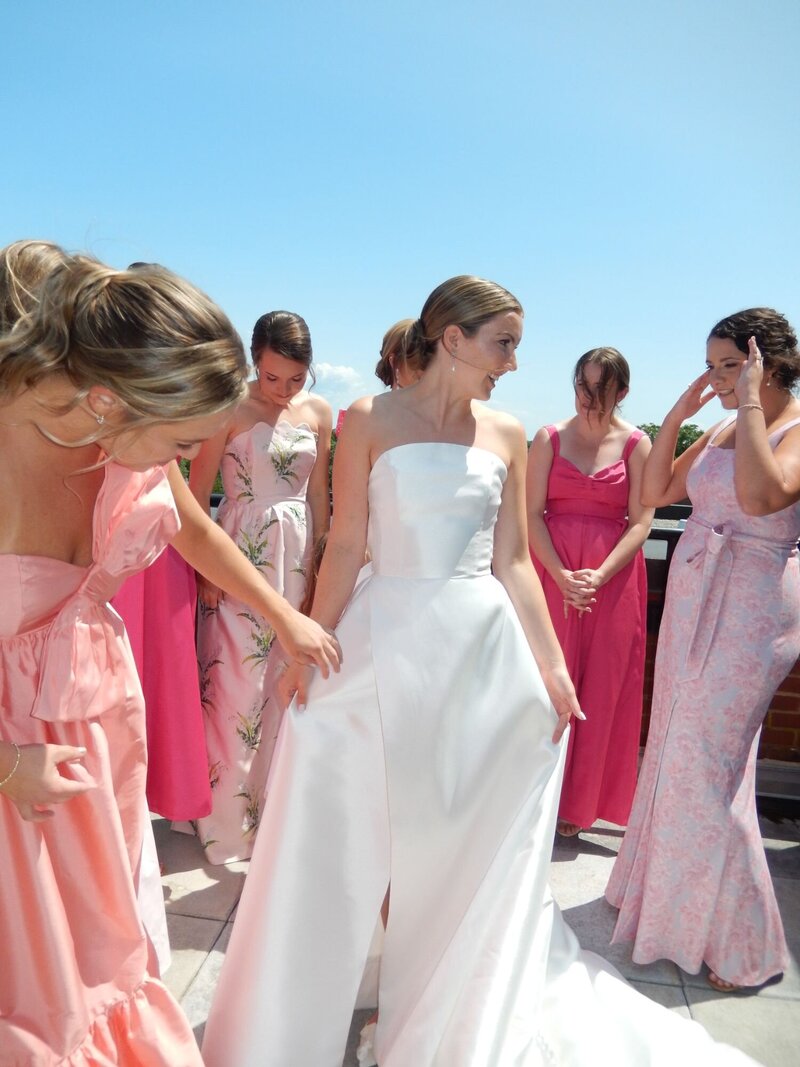 A bride surrounded by her bridesmaids, dancing in the sunlight