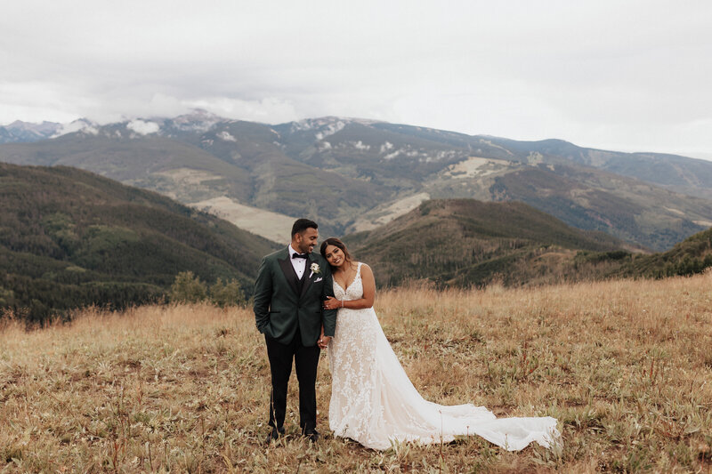 Bride and groom holding hands on top of a mountain