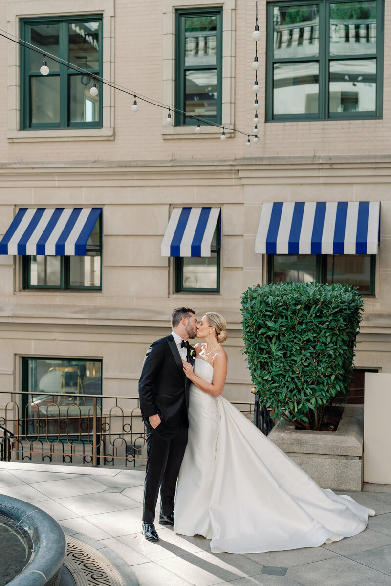 Willard Hotel Wedding in Washington DC | VA Wedding Photographer | bride in long white dress and groom in black tux share a romantic kiss in the courtyard of the Willard Hotel in DC