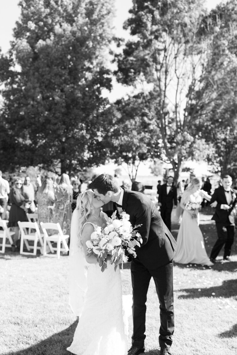 black and white photo bride and groom kissing at wedding ceremony