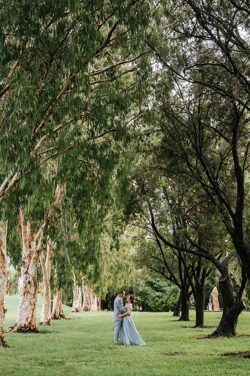 BRide and groom standing outdoors under tall trees