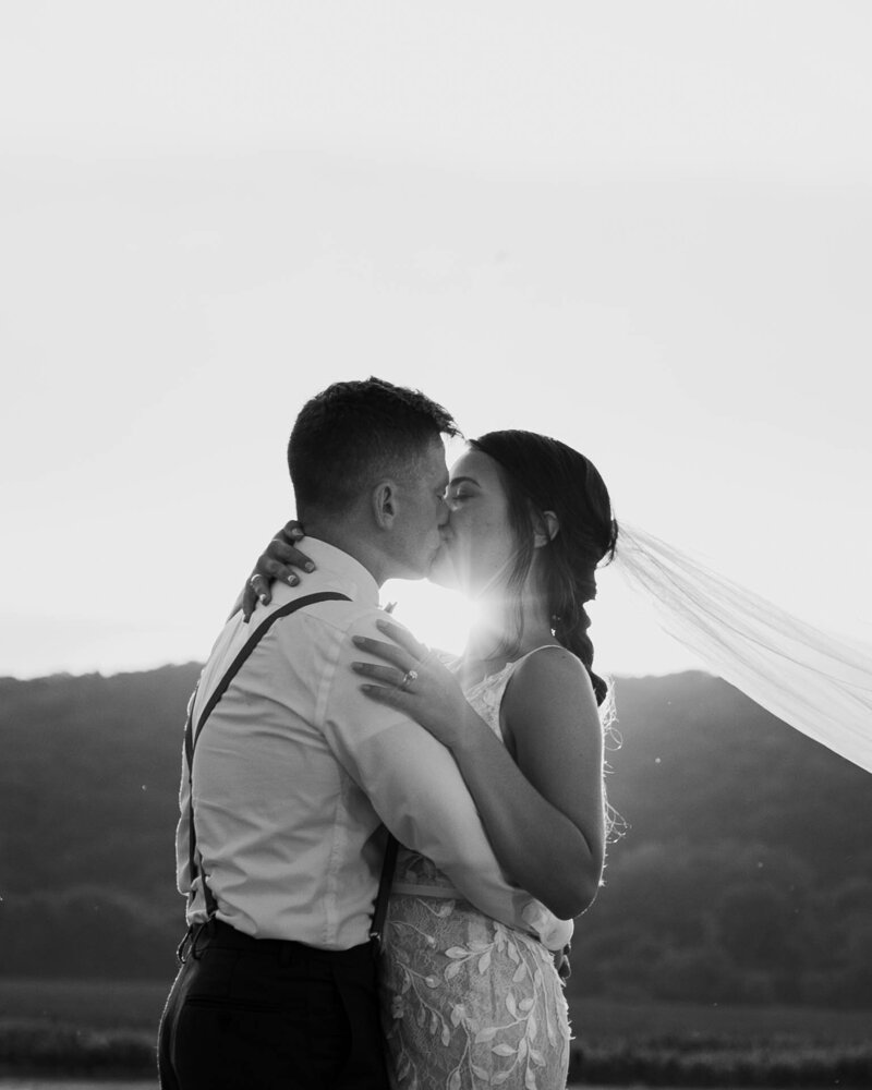 bride and groom kissing  at sunset