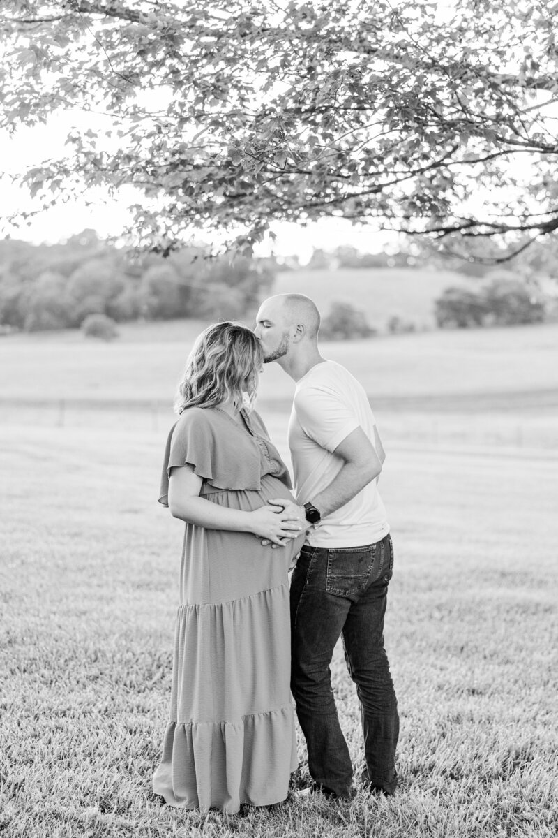 a man kissing his pregnant wife on the forehead