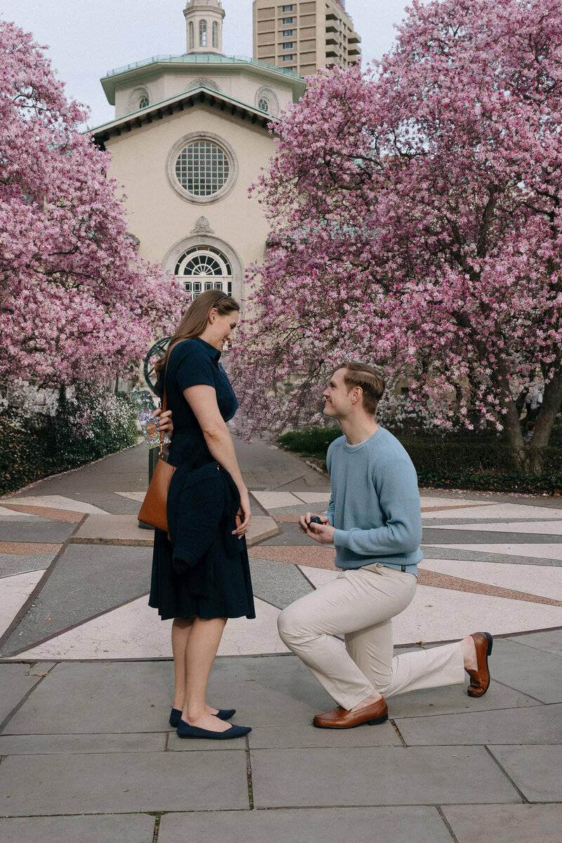 Romantic surprise proposal at the top of the Empire State Building with the NYC skyline in the background.