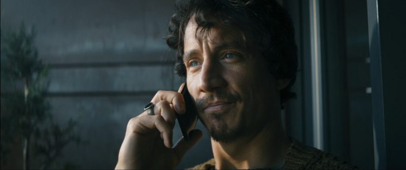 Two people sitting apart on a bench, framed with visual space and cool tones.