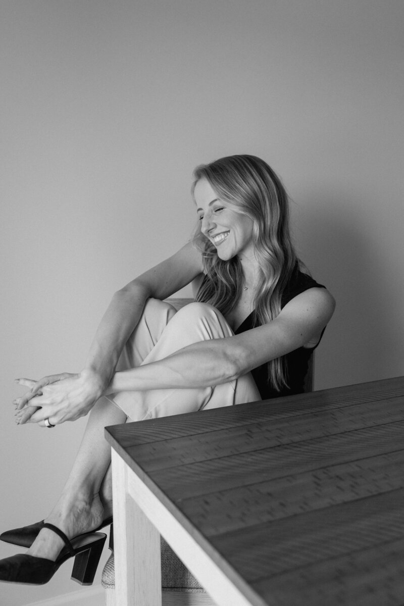 black and white photo of girl laughing at a dining room table