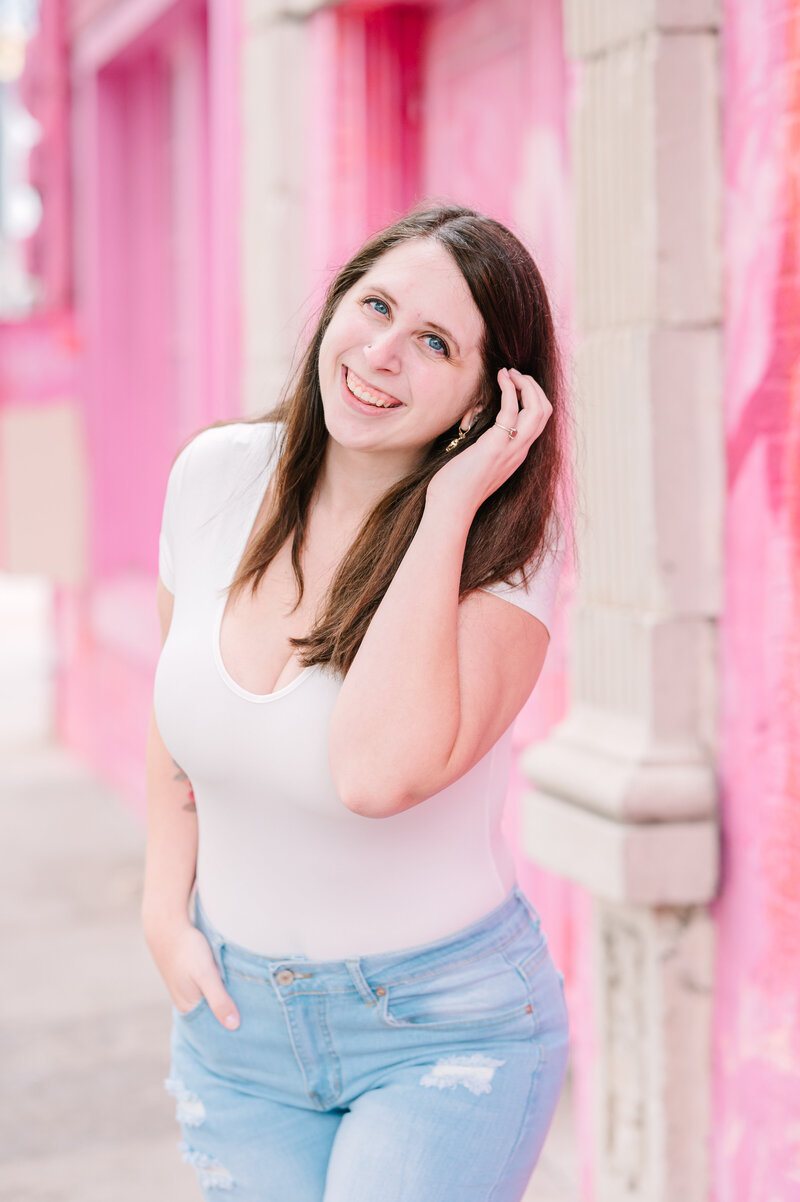 Cait Potter smiling against a pink wall