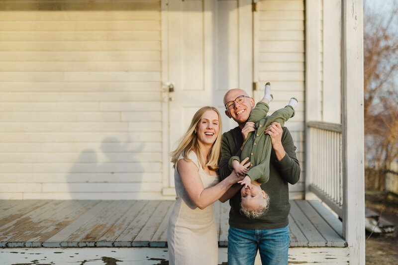 Parents smiling as they hold their child upside down