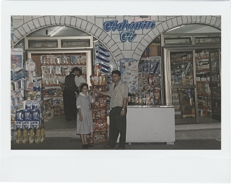 Retro photograph featuring a little girl and her father in front of a small shop