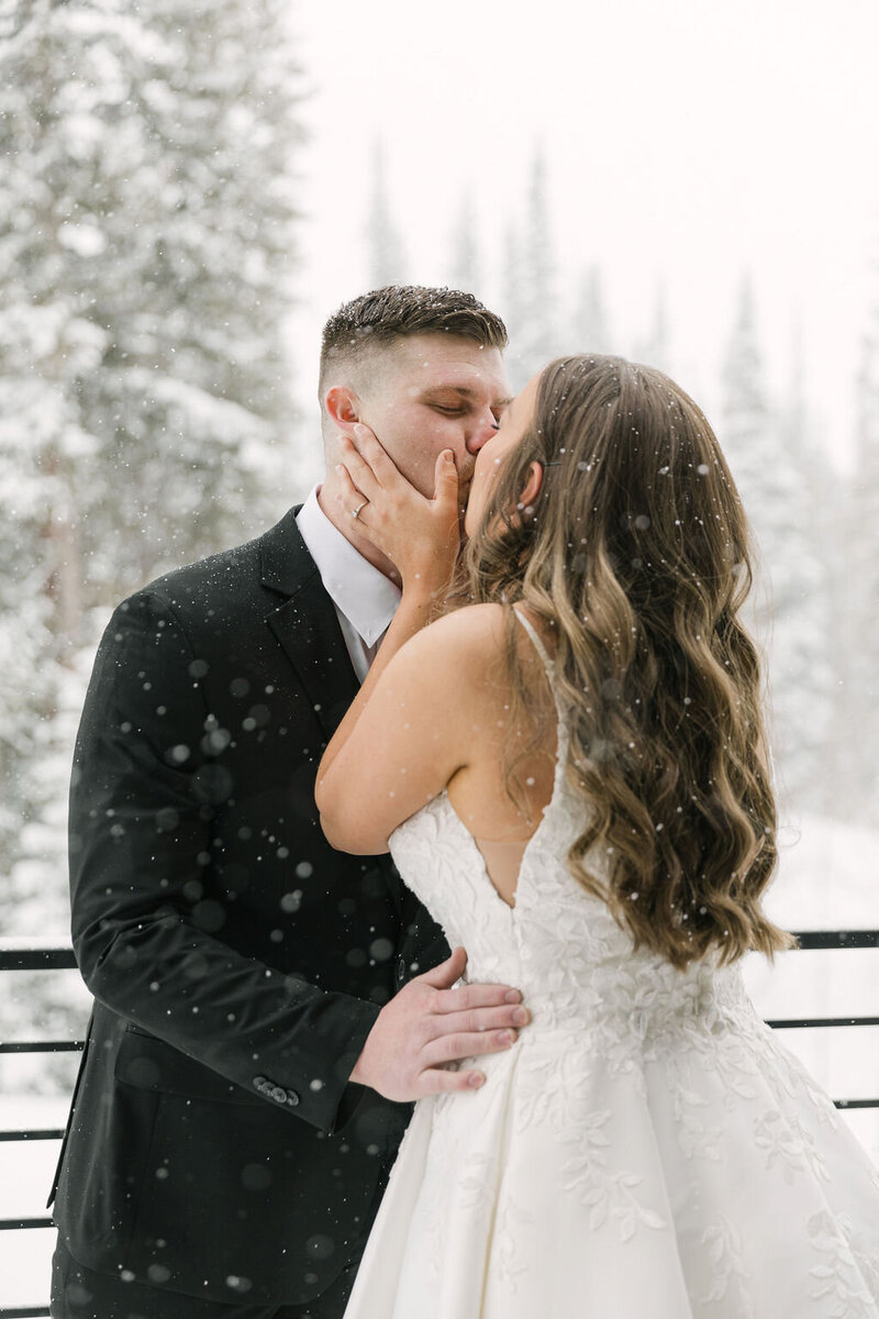 Bride and groom kissing during their snow winter wedding in Colorado captured by Mrs. Ferree Photography