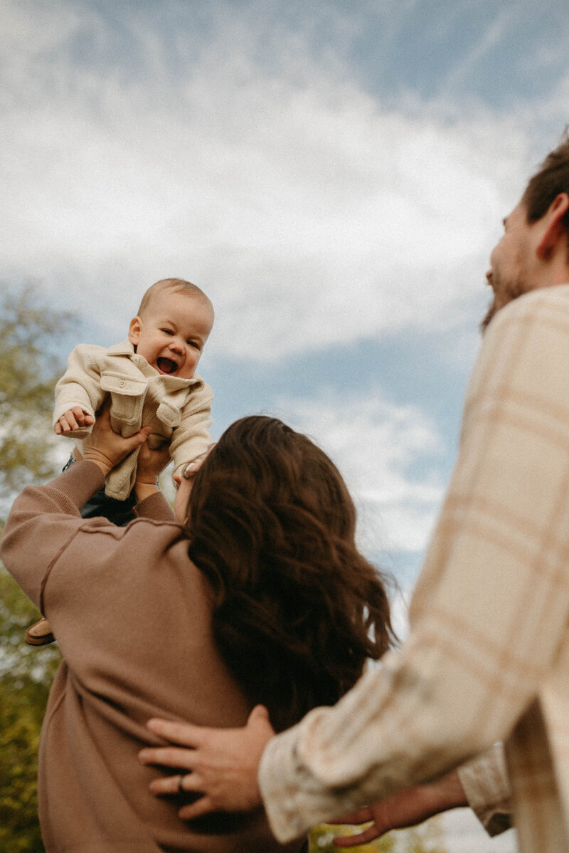 Mother lifting his baby into the air during a joyful and candid family photoshoot in Oregon.