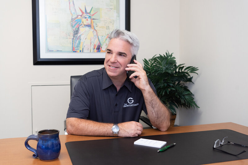 A male business coach talking on the phone in his office.