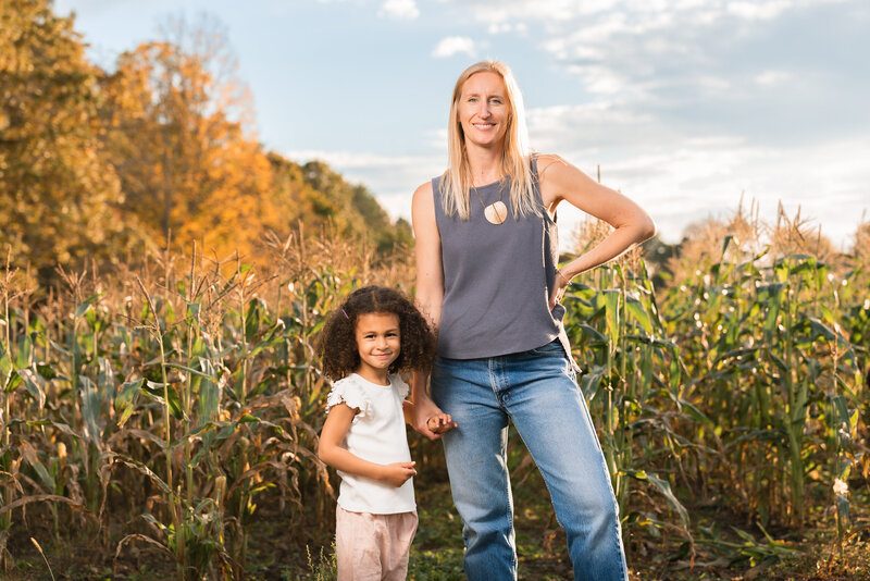 mom and daughter on sunny day in front of corn field