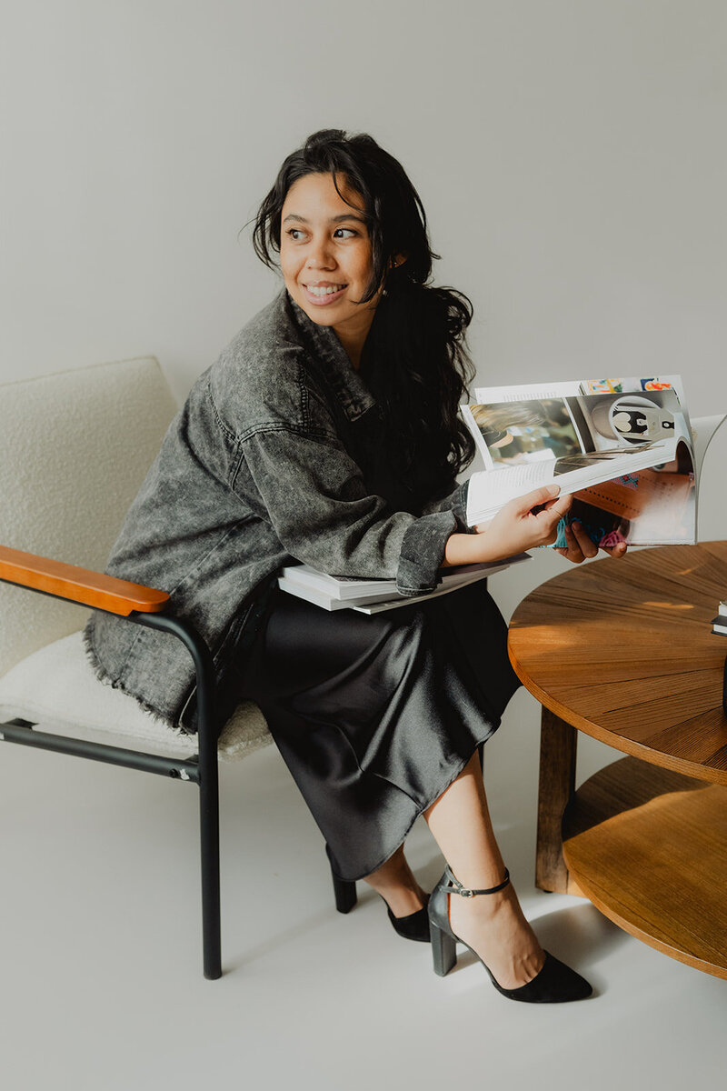 a woman flipping through a creative magazine