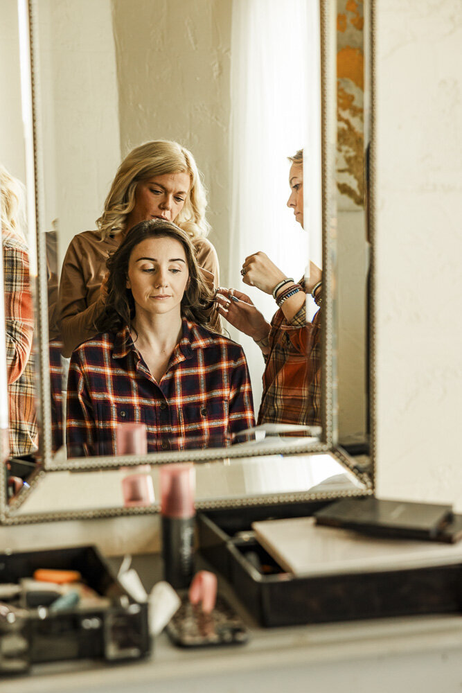Bride getting her hair done in front of a mirror