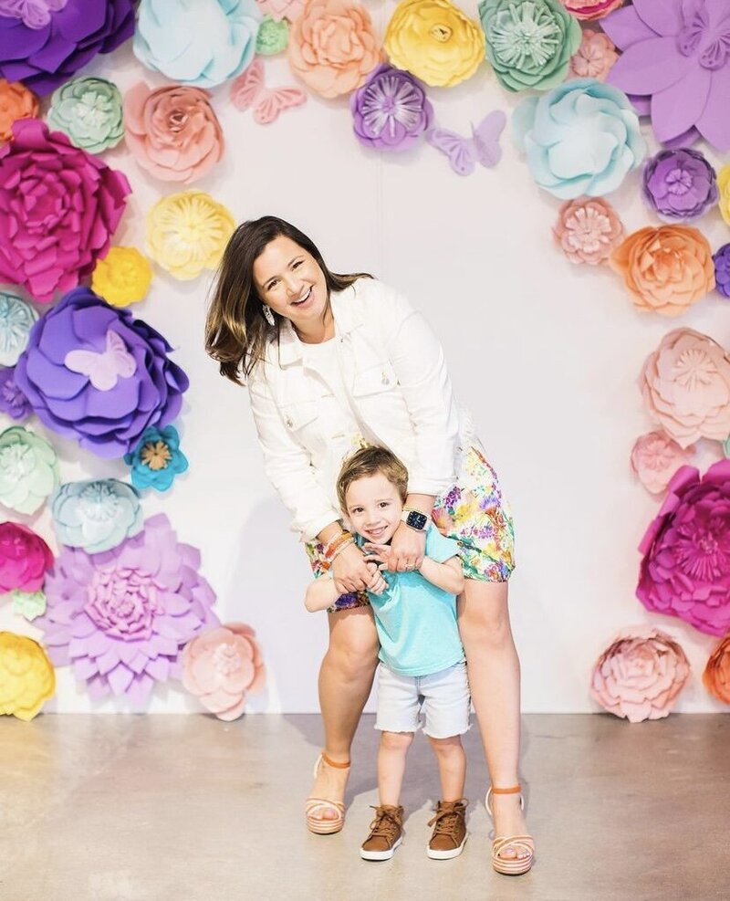 Mother and son posing in front of a floral backdrop design