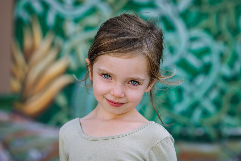 portrait of a kindergarten girl in front of a green mural at school