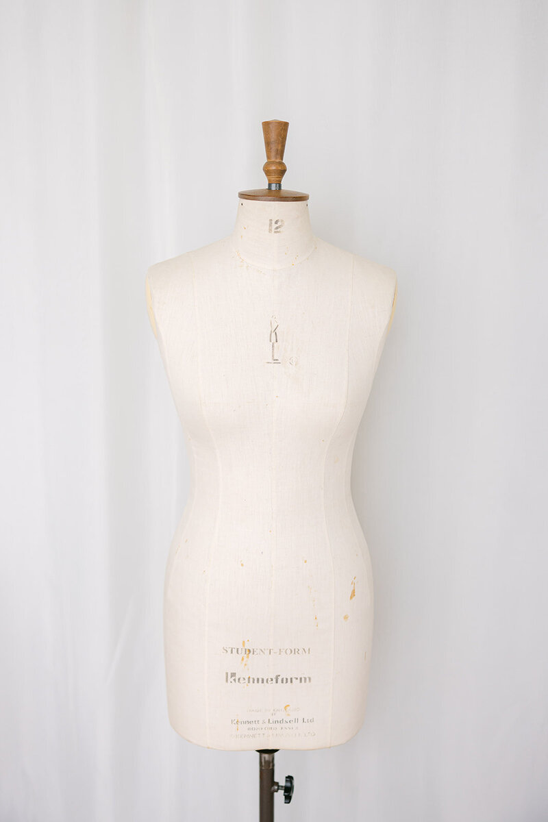 Tailor’s dress form mannequin used for custom bridal gown fittings in a couture sewing studio.