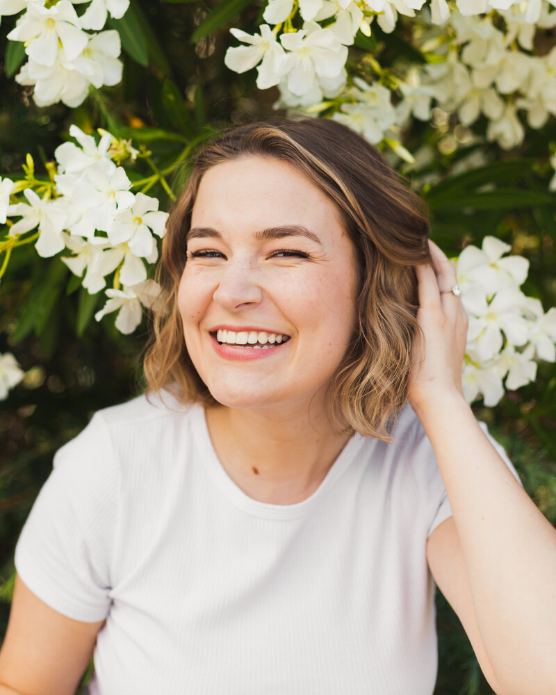 person smiling and pushing their hair back over one ear