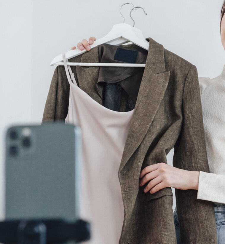 Female holding a dress shirt and blazer to an iPhone