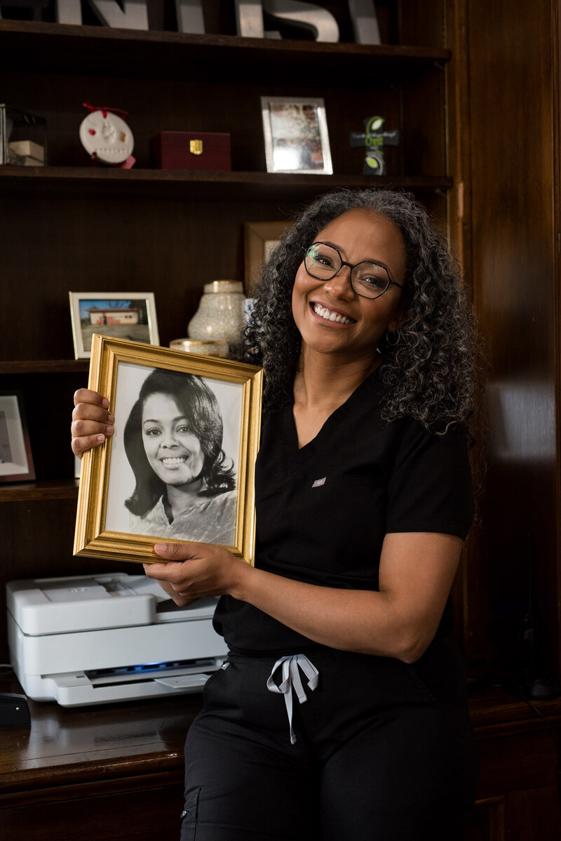 Dr. Dawn Broyles,  Cincinnati Dentist and dental implant specialist, looks at photos and advanced degrees in her lobby of her cincinnati, oh office