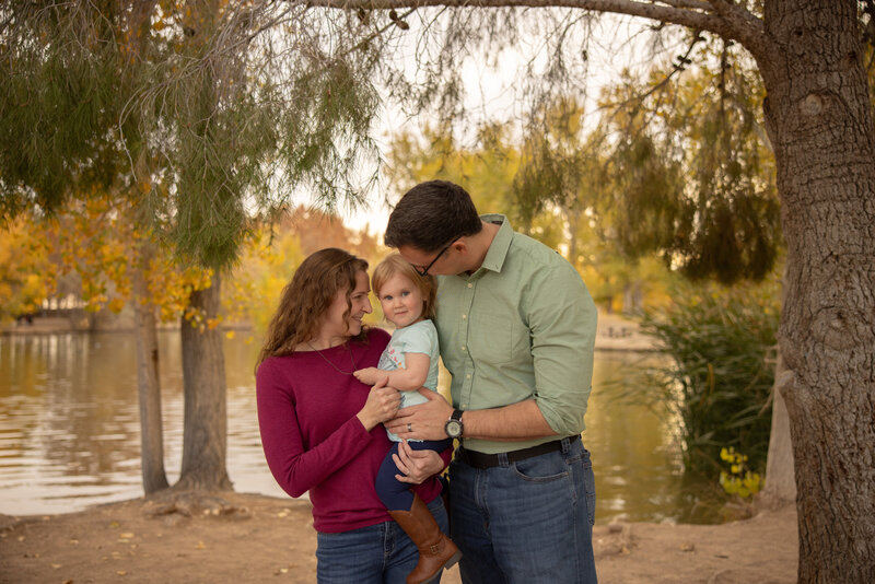husband and wife looking lovingly at their daughter who is smiling towards the camera taken by las vegas portrait photographer alexis dean