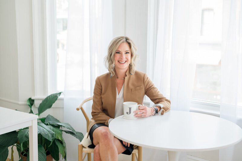 Estate planning attorney Julie Ladimer sitting at a desk holding a coffee mug with a J on it