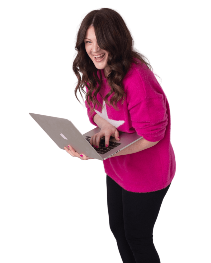 Emily wearing a fuschia sweater smiling and holding a laptop.