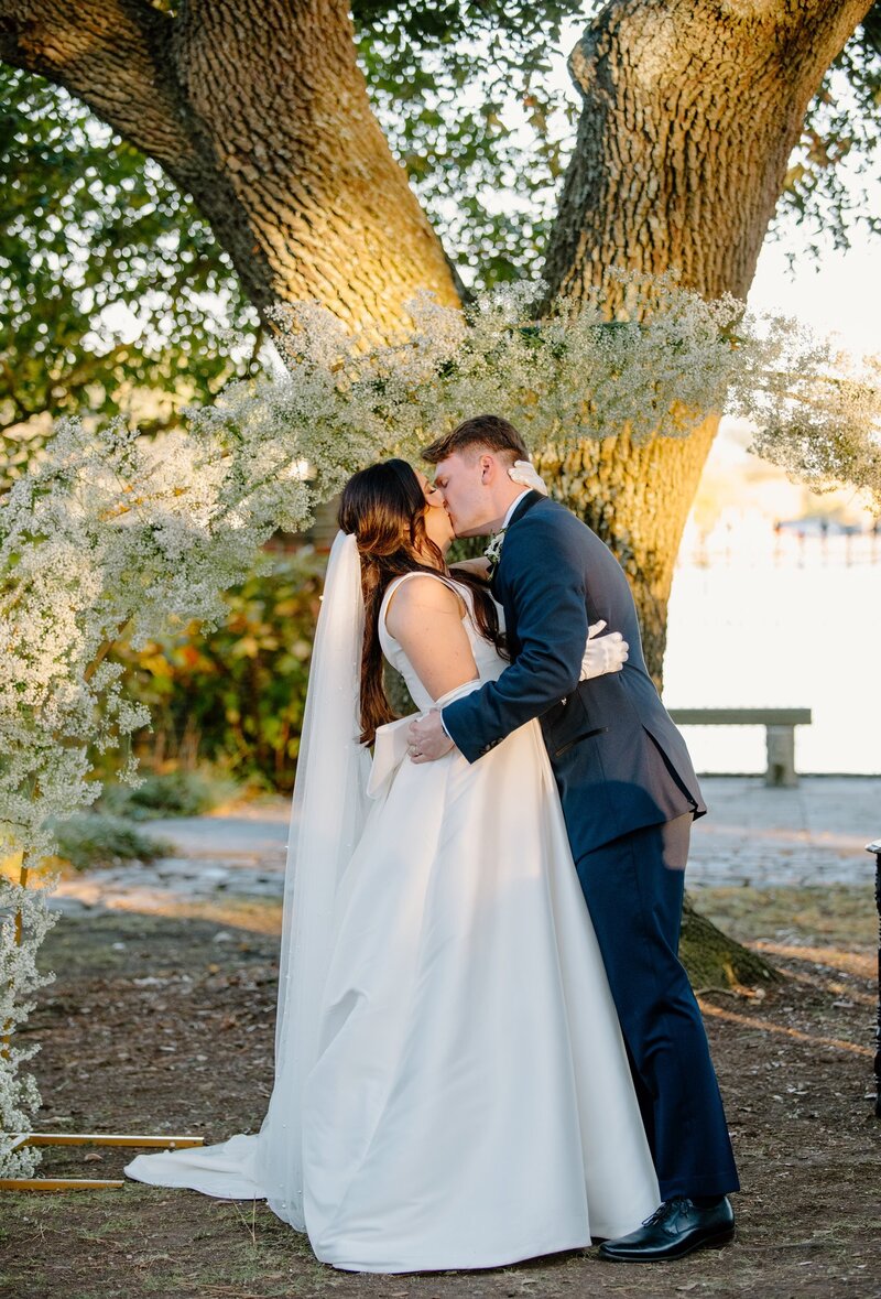Bride and groom kissing under a tree